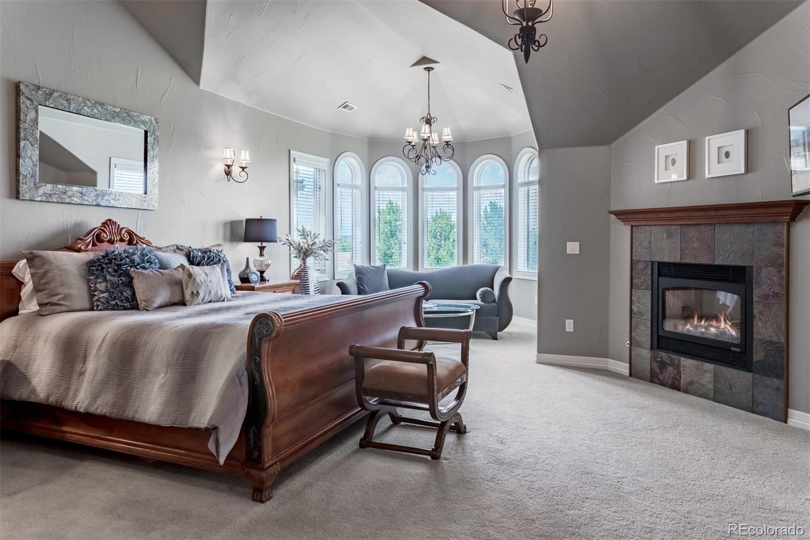 2671 Ranch Reserve Ridge Westminster, CO 80234 - Photo 16 of 35 a spacious bedroom with a bed a chandelier and a fireplace