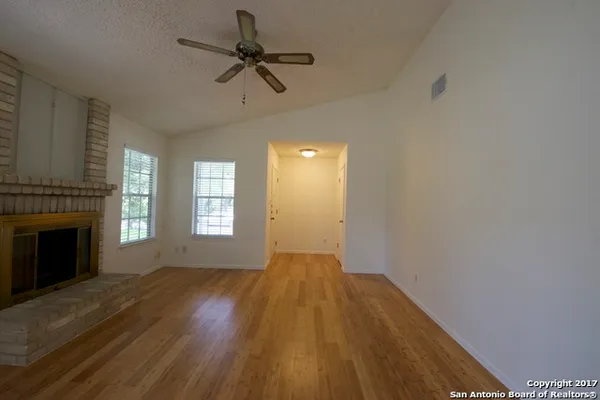 a view of empty room with wooden floor and fireplace