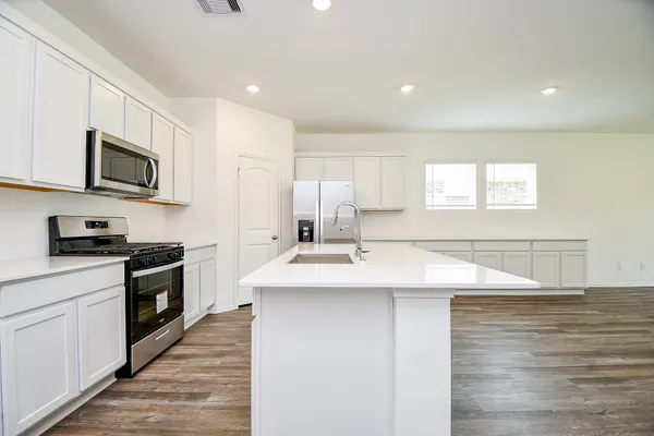 a kitchen with stainless steel appliances granite countertop a sink a stove top oven a counter space and cabinets
