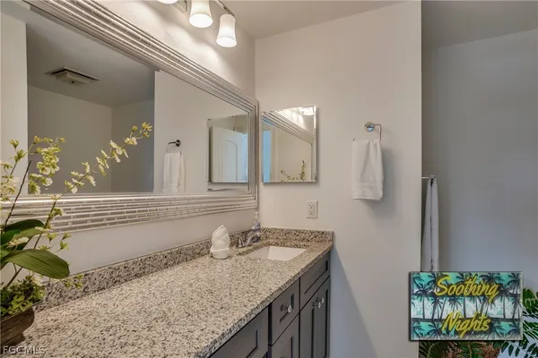 a bathroom with a granite countertop sink and a mirror