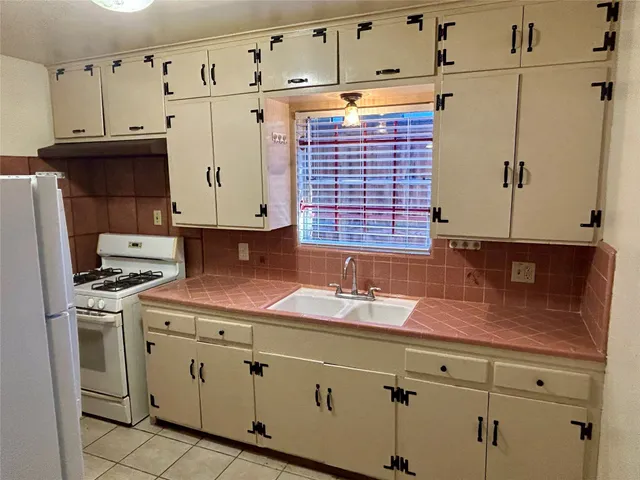 a kitchen with granite countertop a sink a stove and cabinets