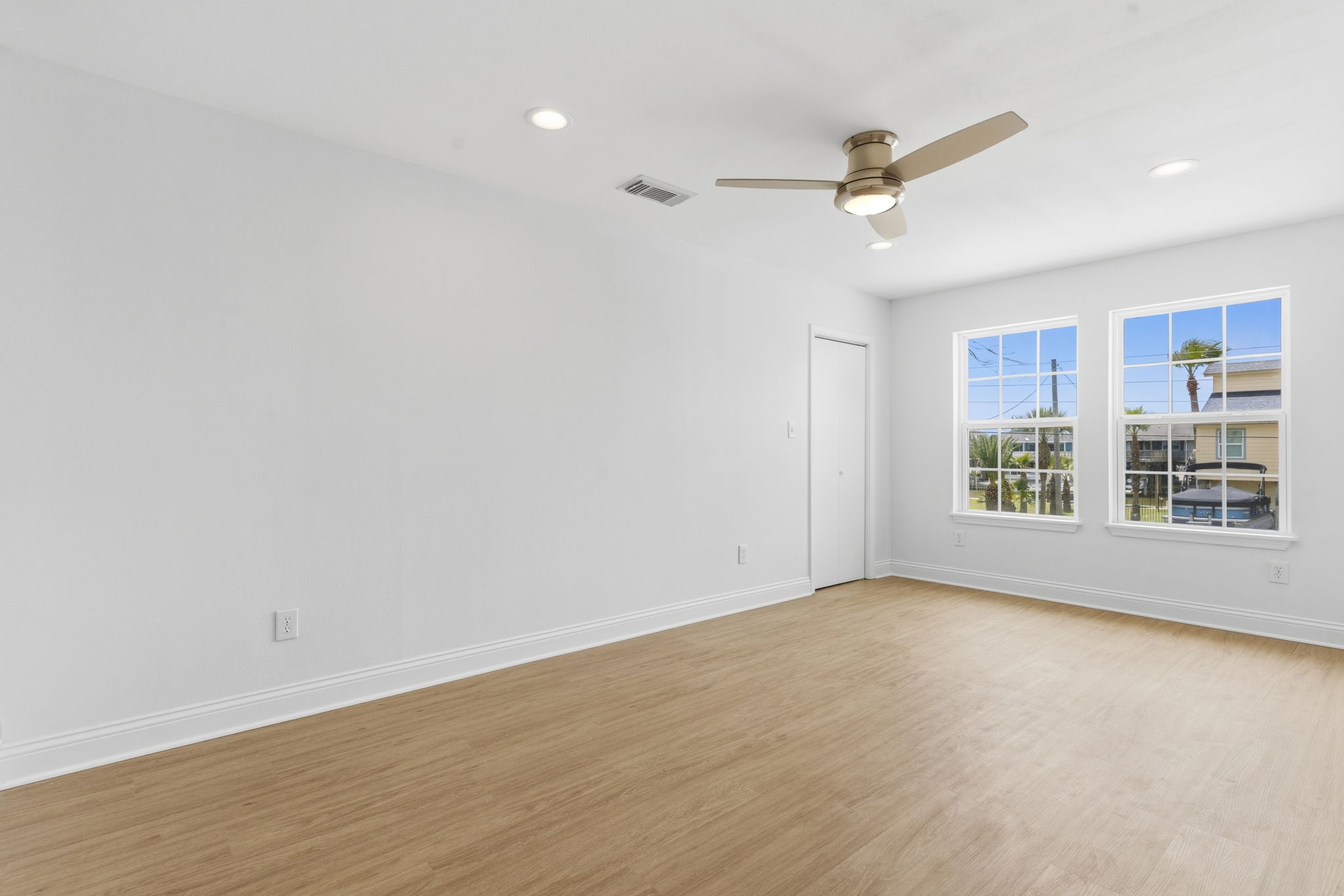 119 Sand Shoals Road Freeport, TX 77541 - Photo 25 of 34 Secondary bedroom — corner windows with palm and canal views across the front of the home, modern brushed-nickel ceiling fan, recessed lighting, and a private closet.