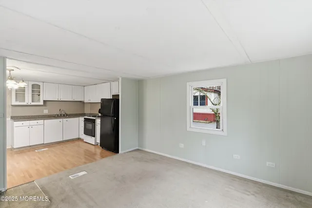 a large white kitchen with granite countertop a refrigerator and white cabinets