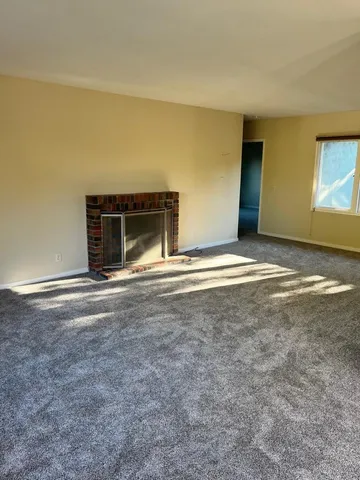 a view of an empty room with window and fireplace