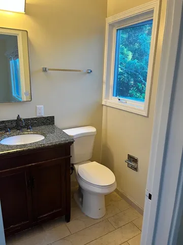 a bathroom with a granite countertop toilet a sink and mirror