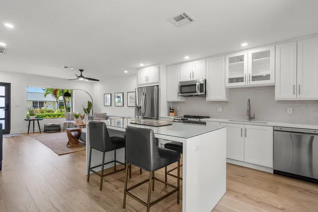 a kitchen with stainless steel appliances granite countertop a stove top oven a sink dishwasher a dining table and chairs with wooden floor