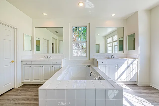 a spacious bathroom with a double vanity sink a mirror and a bathtub