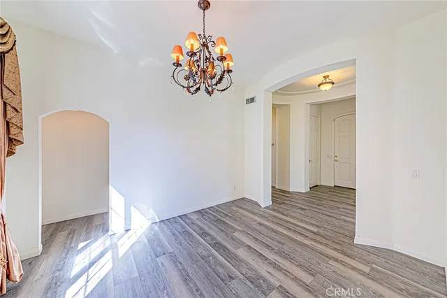 an empty room with wooden floor fireplace and windows