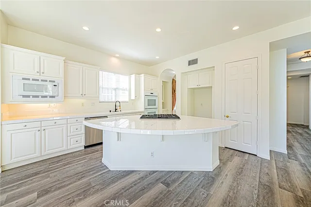 a large white kitchen with sink a refrigerator and a stove top oven