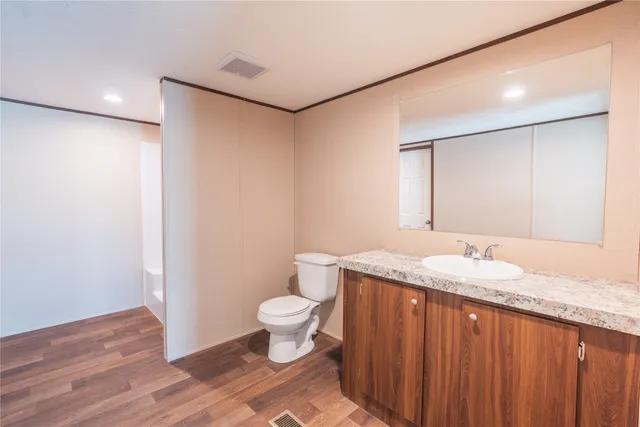 a bathroom with a granite countertop sink a toilet and a mirror