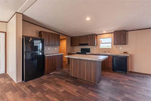 a kitchen with stainless steel appliances granite countertop a refrigerator a sink dishwasher a stove with wooden cabinets and a refrigerator