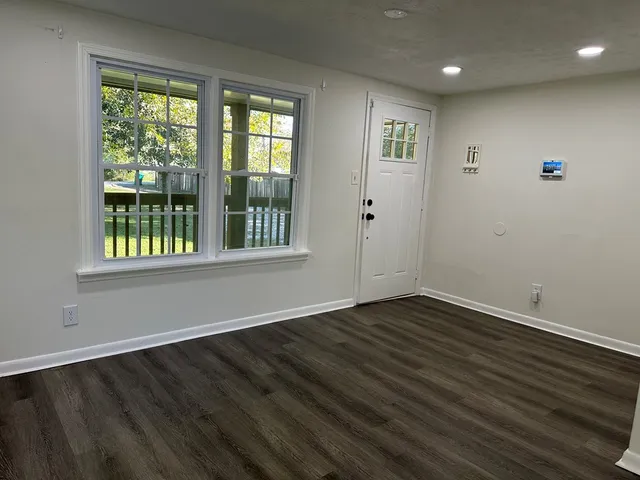 an empty room with wooden floor and windows