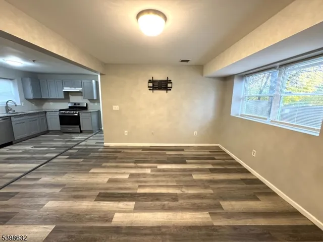 a view of a kitchen with kitchen island a sink wooden floor and a large window