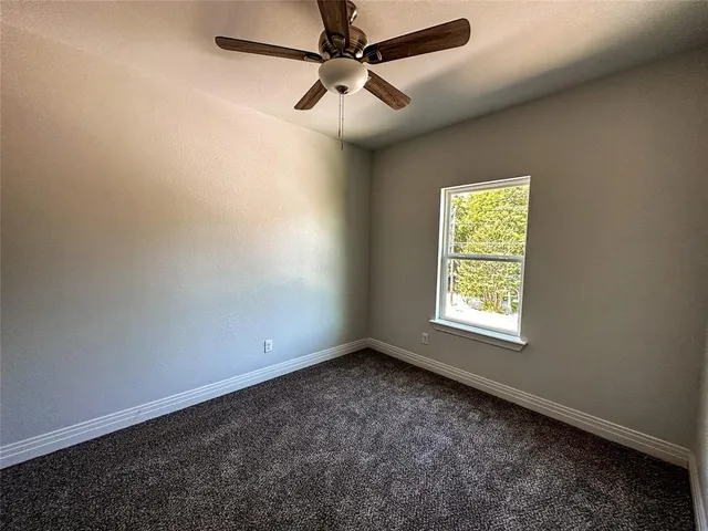 an empty room with a window and a fan