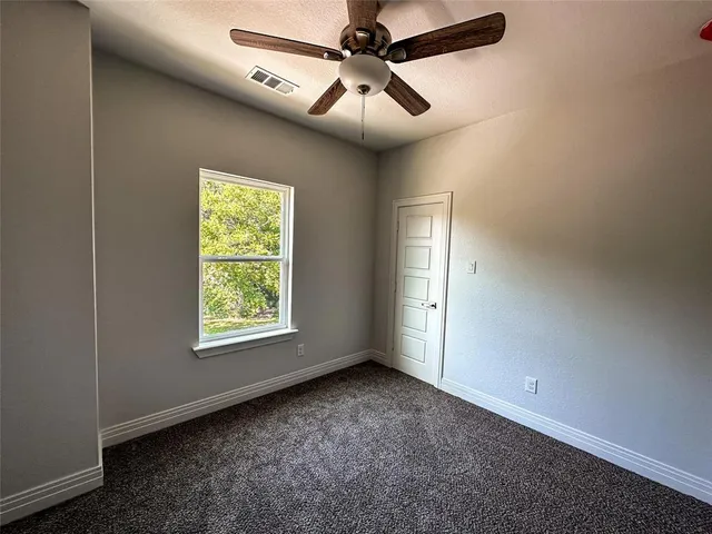 an empty room with windows and fan