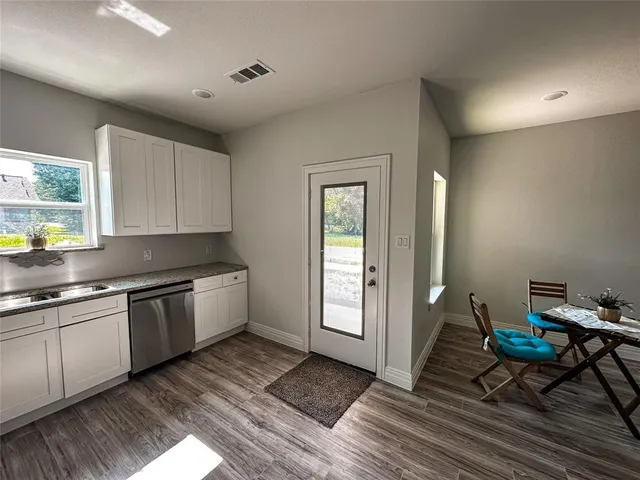 a kitchen with granite countertop a stove a sink and white cabinets with wooden floor