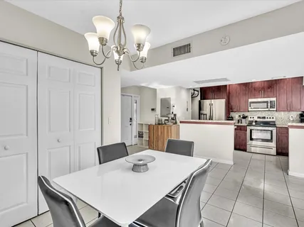 a kitchen with stainless steel appliances granite countertop a sink dishwasher a stove a refrigerator white cabinets with a dining table and chairs