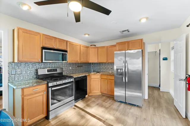 a kitchen with stainless steel appliances granite countertop a refrigerator a stove top oven a sink and dishwasher with wooden floor