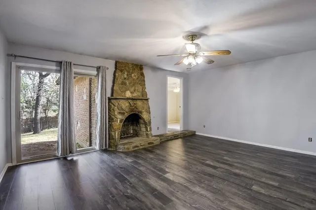 a view of an empty room with wooden floor fireplace and a window