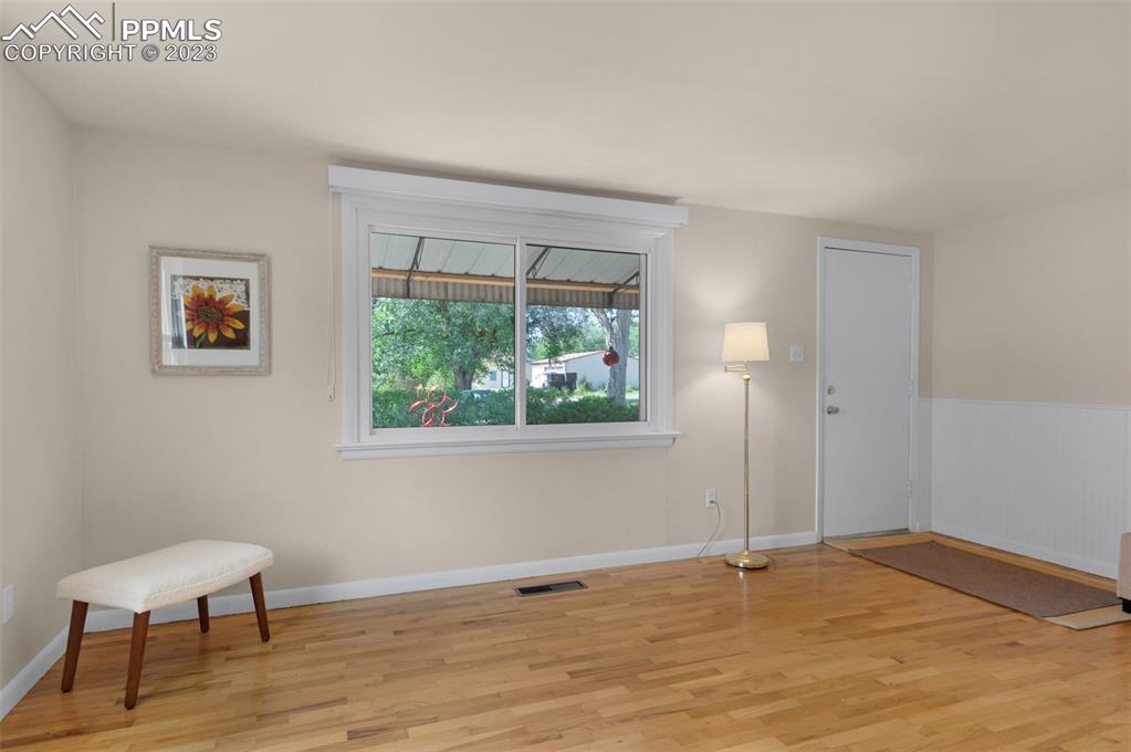 1011 Sunset Road Colorado Springs, CO 80909 - Photo 8 of 46 a view of an empty room with a window and wooden floor