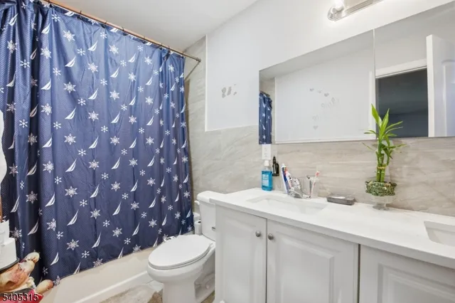 a bathroom with a granite countertop sink and a toilet