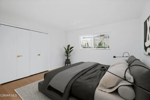 a bedroom with a bed and a potted plant on the dresser