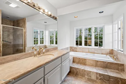a spacious bathroom with a tub a sink and a large window