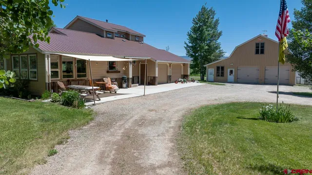a backyard of a house with table and chairs under an umbrella