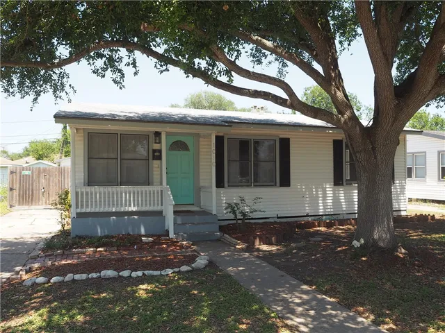 a front view of a house with a tree
