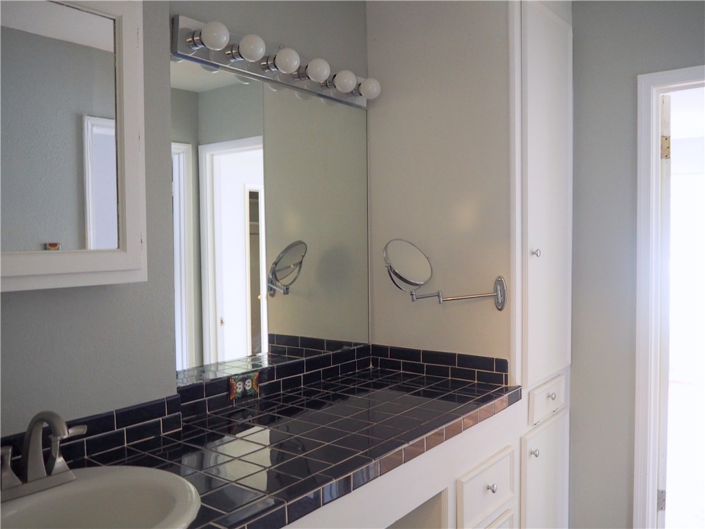 1010 Deforrest Street Corpus Christi, TX 78404 - Photo 18 of 22 a bathroom with a granite countertop sink a mirror and shower
