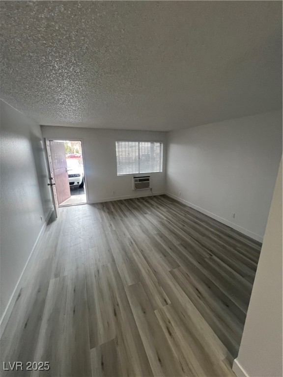 797 East Harmon Avenue, Unit 7 Las Vegas, NV 89119 - Photo 9 of 12 Unfurnished living room featuring healthy amount of natural light, a textured ceiling, and wood finished floors
