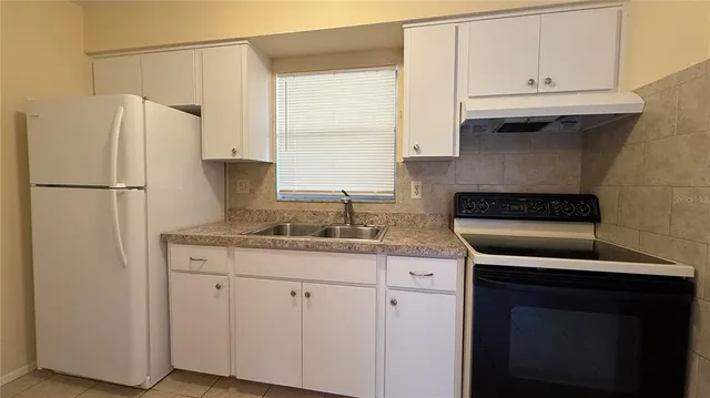 a kitchen with granite countertop a refrigerator sink and cabinets
