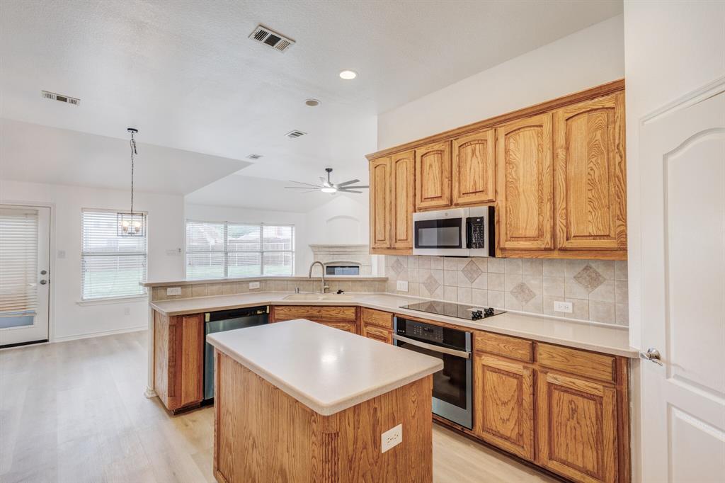 12405 Ark Road Frisco, TX 75035 - Photo 17 of 34 Kitchen featuring light countertops, stainless steel appliances, a peninsula, a center island, and pendant lighting