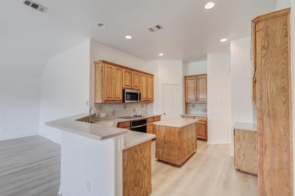 12405 Ark Road Frisco, TX 75035 - Photo 19 of 34 Kitchen with a kitchen island, light wood finished floors, light countertops, decorative backsplash, and recessed lighting