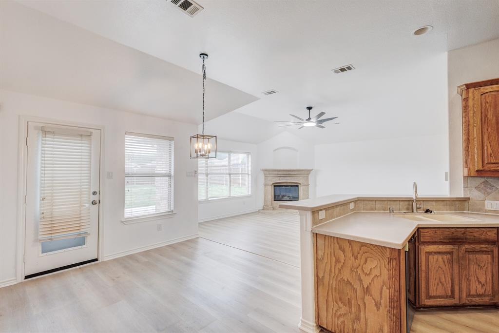12405 Ark Road Frisco, TX 75035 - Photo 33 of 34 Kitchen with open floor plan, a glass covered fireplace, light countertops, a peninsula, and hanging lights