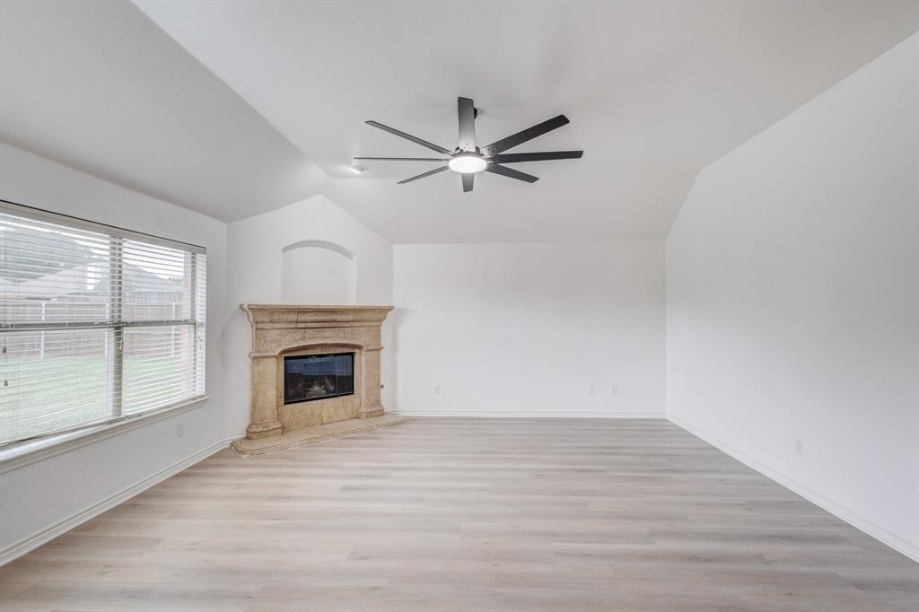 12405 Ark Road Frisco, TX 75035 - Photo 21 of 34 Unfurnished living room with light wood finished floors, ceiling fan, vaulted ceiling, and a fireplace