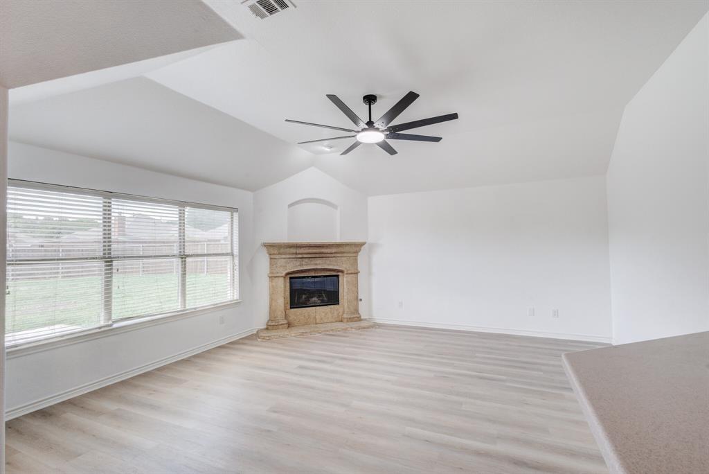 12405 Ark Road Frisco, TX 75035 - Photo 24 of 34 Unfurnished living room with light wood-style flooring, ceiling fan, vaulted ceiling, and a premium fireplace