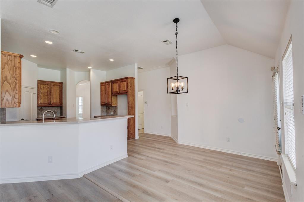 12405 Ark Road Frisco, TX 75035 - Photo 27 of 34 Kitchen with backsplash, plenty of natural light, light wood-type flooring, wood finish cabinets, and lofted ceiling