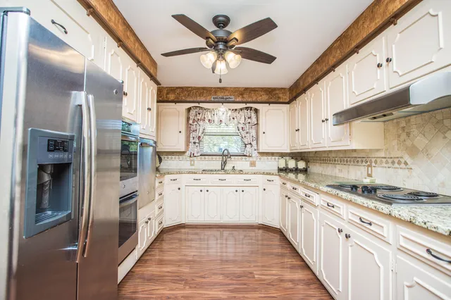 a kitchen with granite countertop a sink stainless steel appliances and cabinets