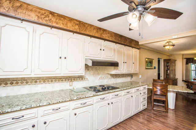 a kitchen with granite countertop a sink a counter space appliances and cabinets