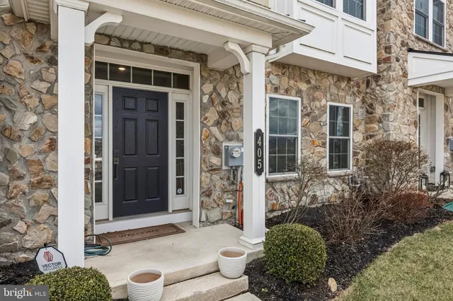 front view of a brick house with a large window and potted plants