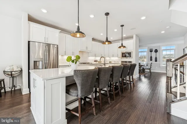 a kitchen with stainless steel appliances kitchen island granite countertop a table chairs and a refrigerator