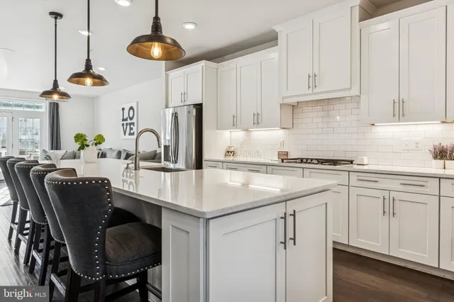 a kitchen with stainless steel appliances granite countertop a sink a stove and chairs with white cabinets