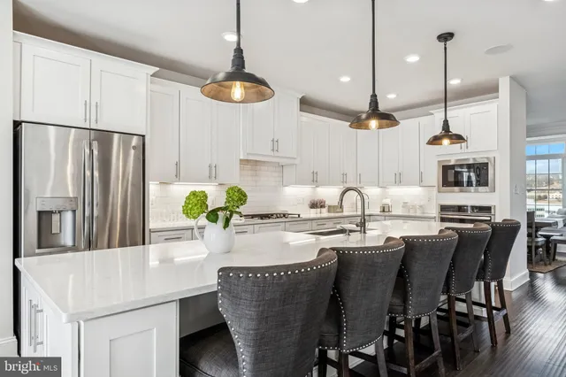 a kitchen with stainless steel appliances granite countertop a table chairs and a refrigerator