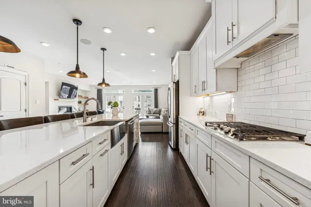 a white kitchen with stainless steel appliances granite countertop lots of counter space a sink and cabinets