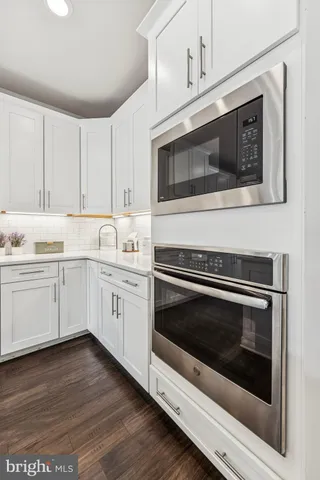 a kitchen with stainless steel appliances white cabinets and a stove top oven
