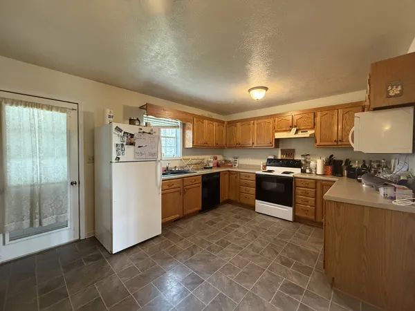a kitchen with stainless steel appliances granite countertop a stove top oven a sink and a refrigerator
