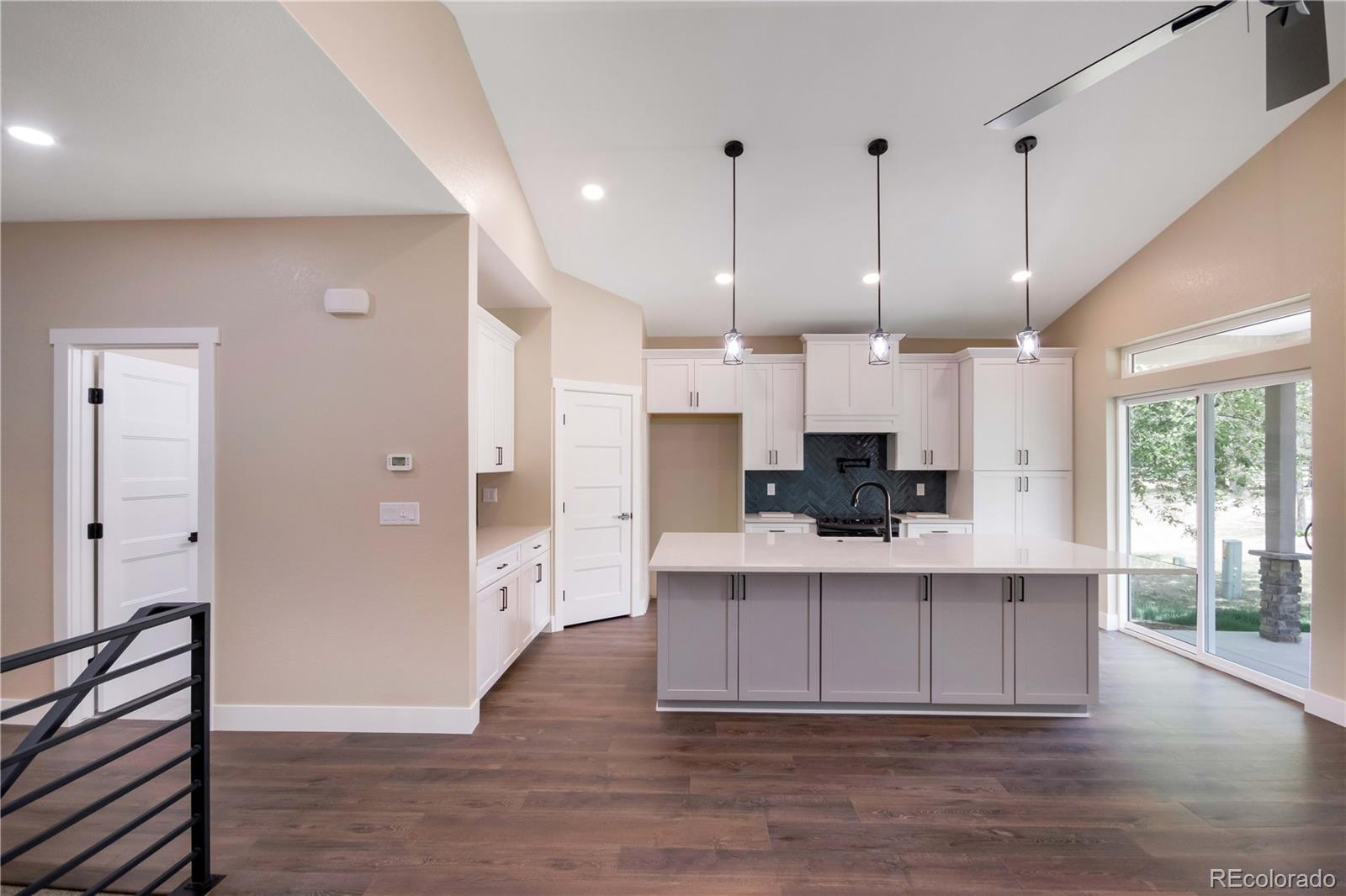 1220 Swainson Road Eaton, CO 80615 - Photo 12 of 35 a large white kitchen with kitchen island a stove a refrigerator a sink dishwasher and white cabinets with wooden floor