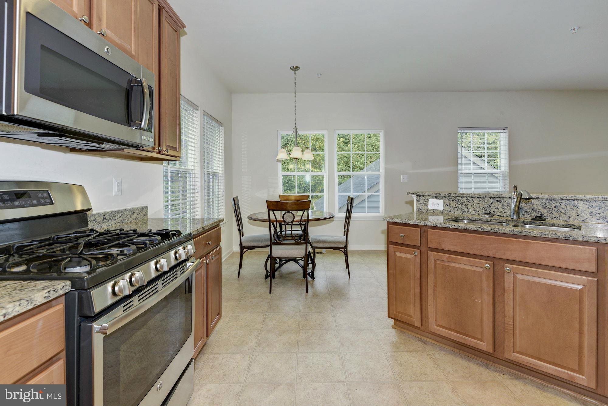 2644 St Marys View Road Accokeek, MD 20607 - Photo 15 of 29 a kitchen with stainless steel appliances granite countertop a stove top oven a sink dishwasher a dining table and chairs with wooden floor