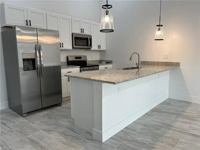 a kitchen with stainless steel appliances granite countertop a refrigerator a sink a stove a microwave and wooden floor